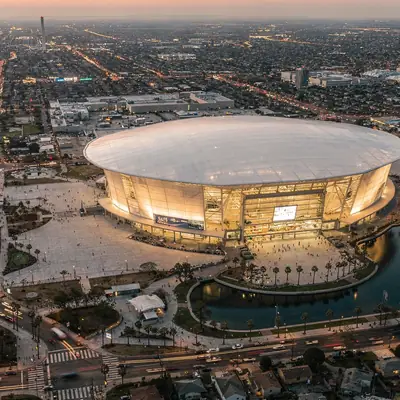 Aerial view at dusk of the stadium, its lake and surrounding neighborhoods in Inglewood, California