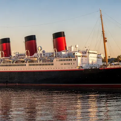The Queen Mary ocean liner docked in Long Beach, California at golden hour