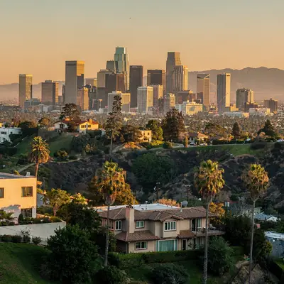 Downtown Los Angeles skyline at golden hour above hillside homes and palm trees in Los Angeles, California