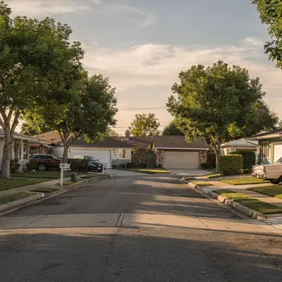 Street of 1950s ranch homes with lawns and mature trees in Norwalk, California